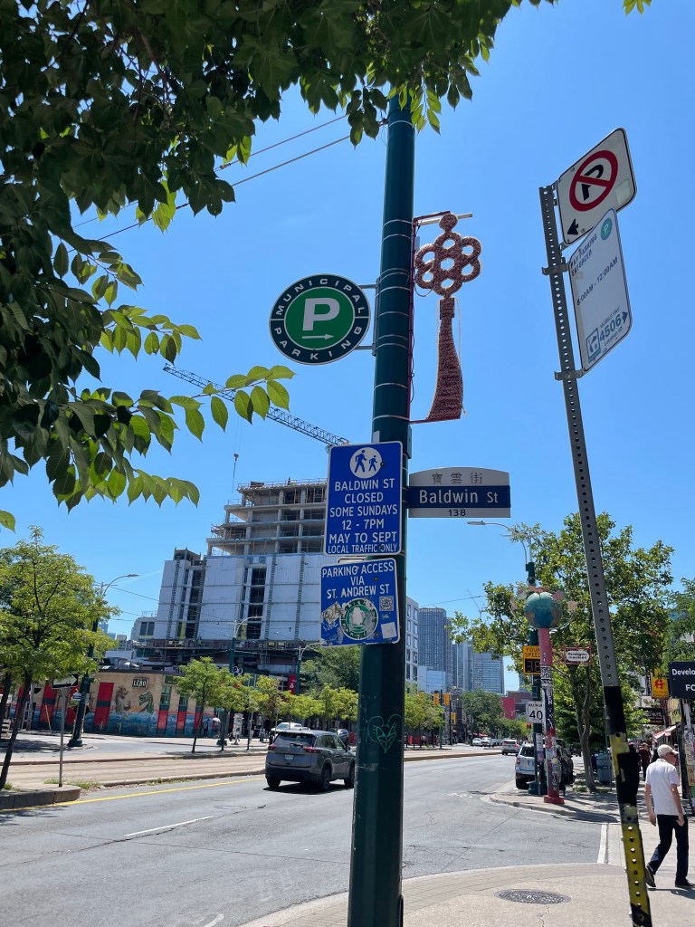 A pole on a street with many signs about parking and occasional street closures - next to another pole with more signs about parking.