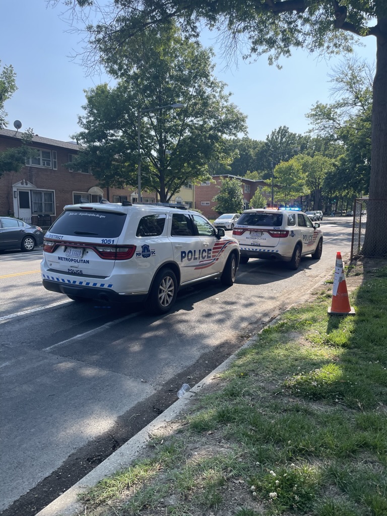 Two police SUVs are parked in a bike lane despite plentiful street parking along the curb.